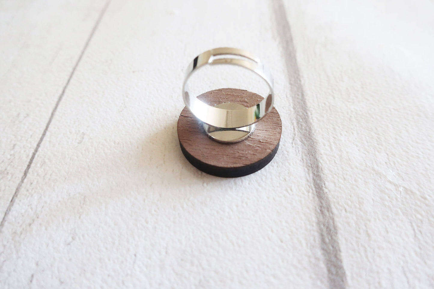 Silver ring on a wooden ring back against a white background