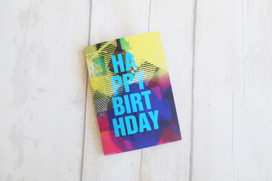 Colorful birthday card with 'Happy Birthday' text on a white wooden surface