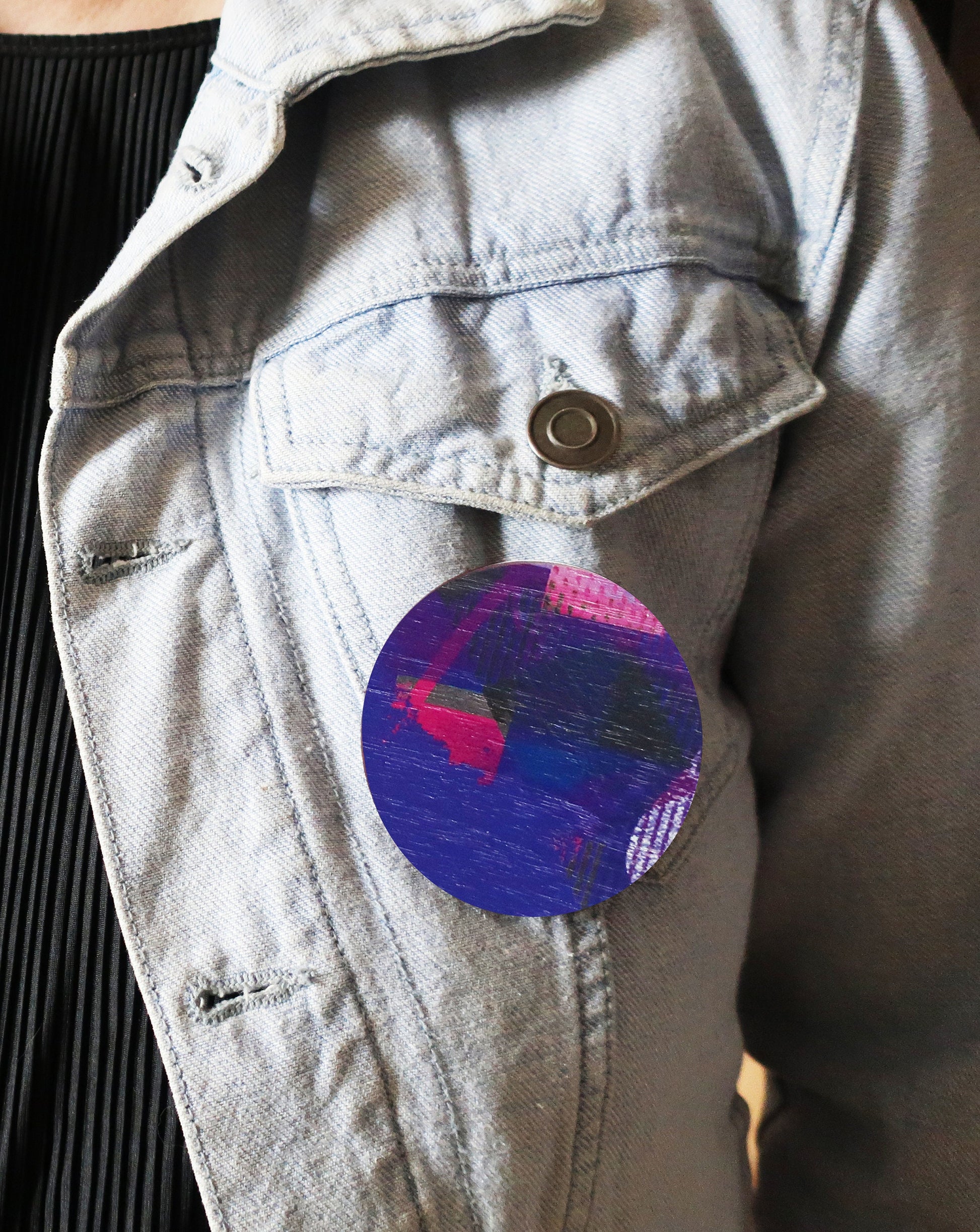 Light blue denim jacket with a colorful circular brooch on the chest.