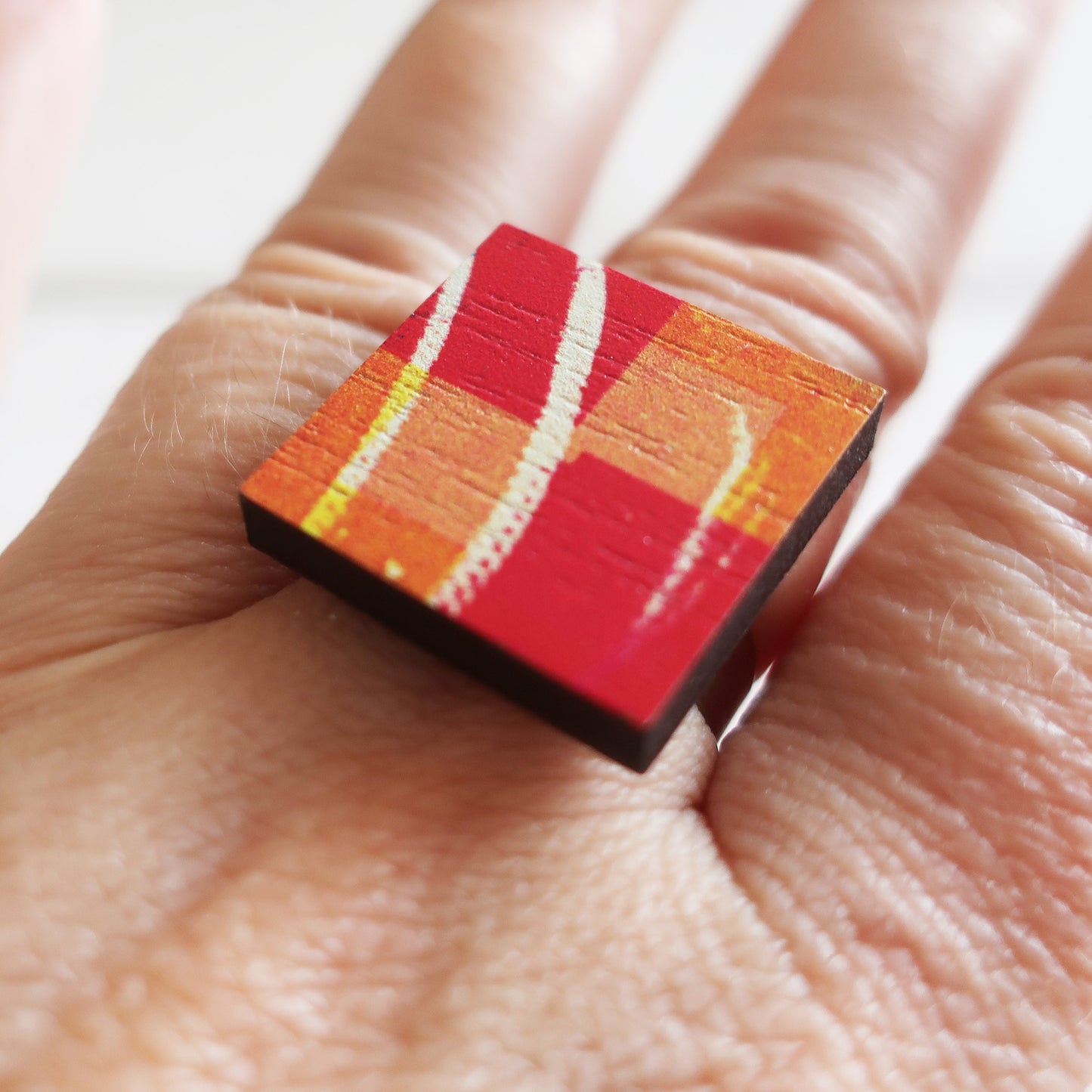 Colorful square ring on a person's finger with a white background