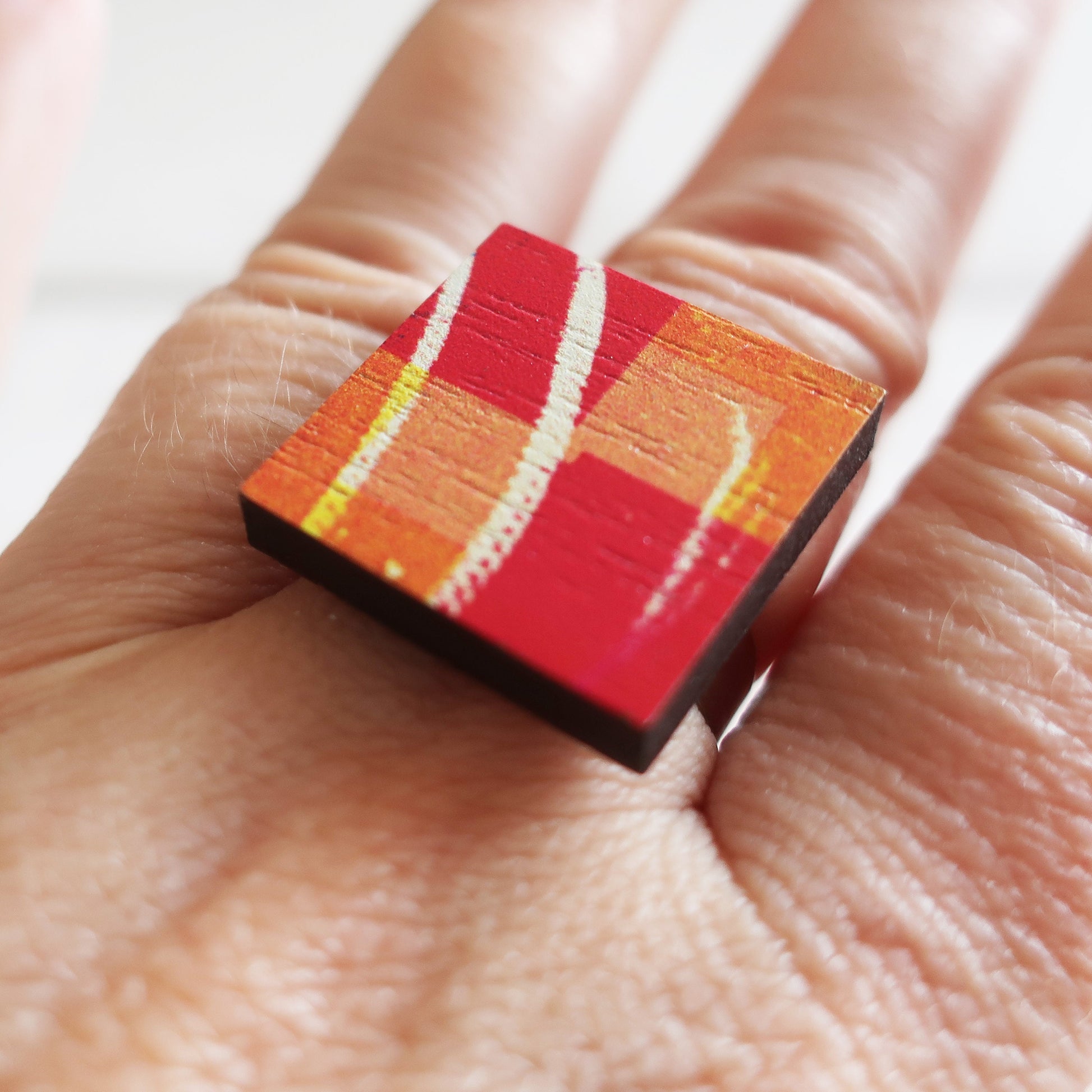 Colorful square ring on a person's finger with a white background