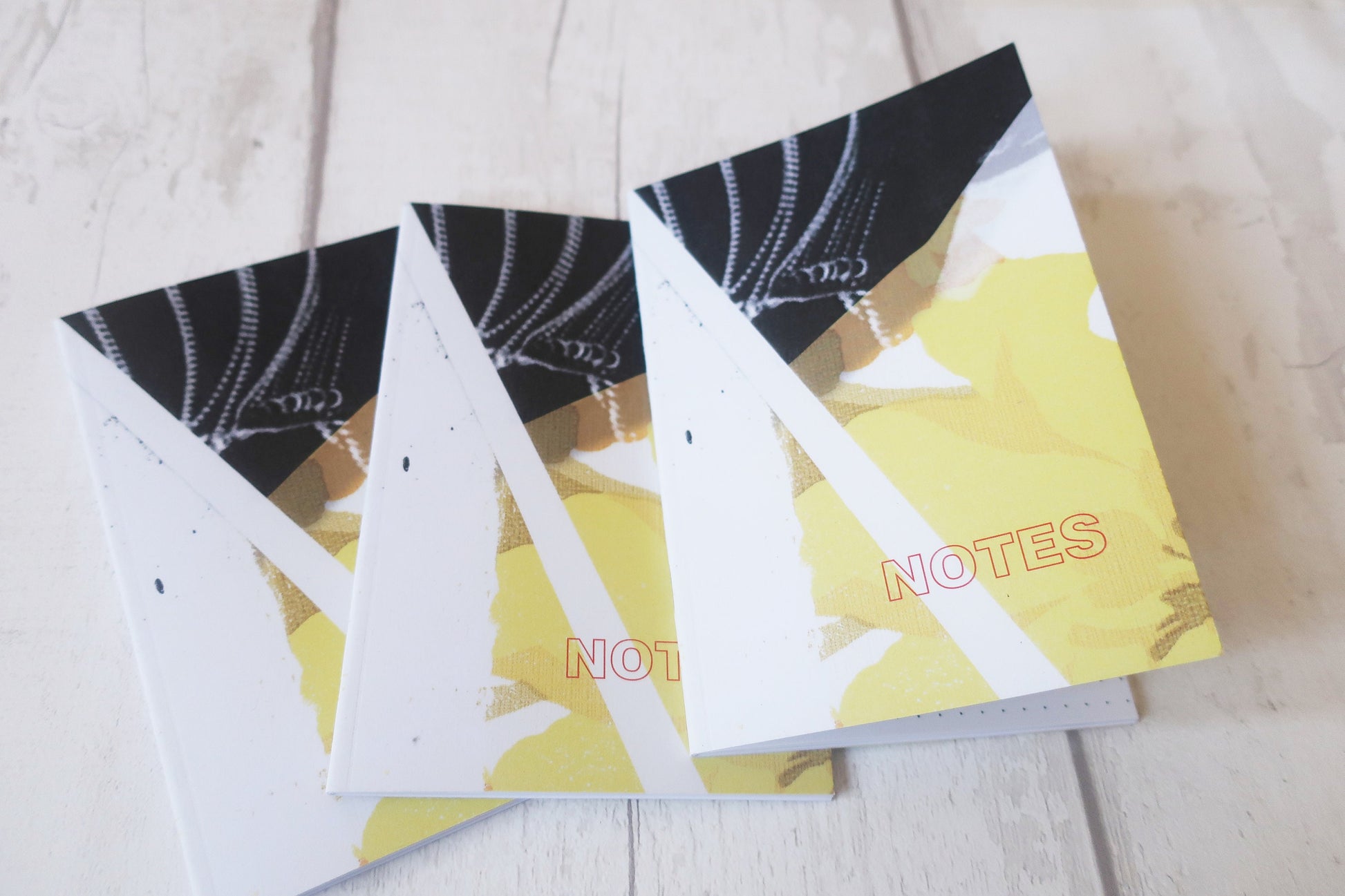 Three  notebooks with black and white designs on a light wooden surface