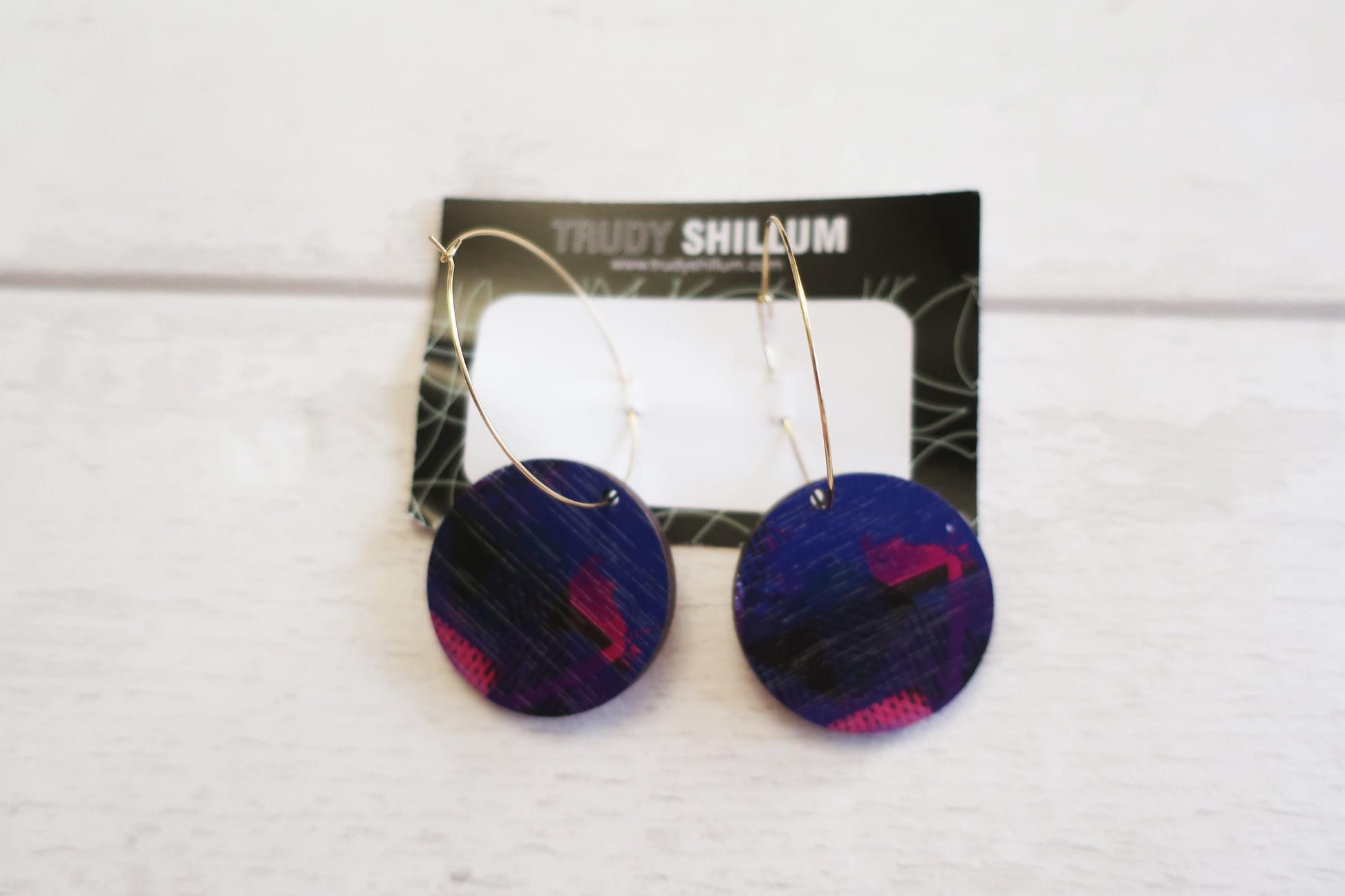 Pair of blue earrings with pink accents on a Trudy Shillum branded card.