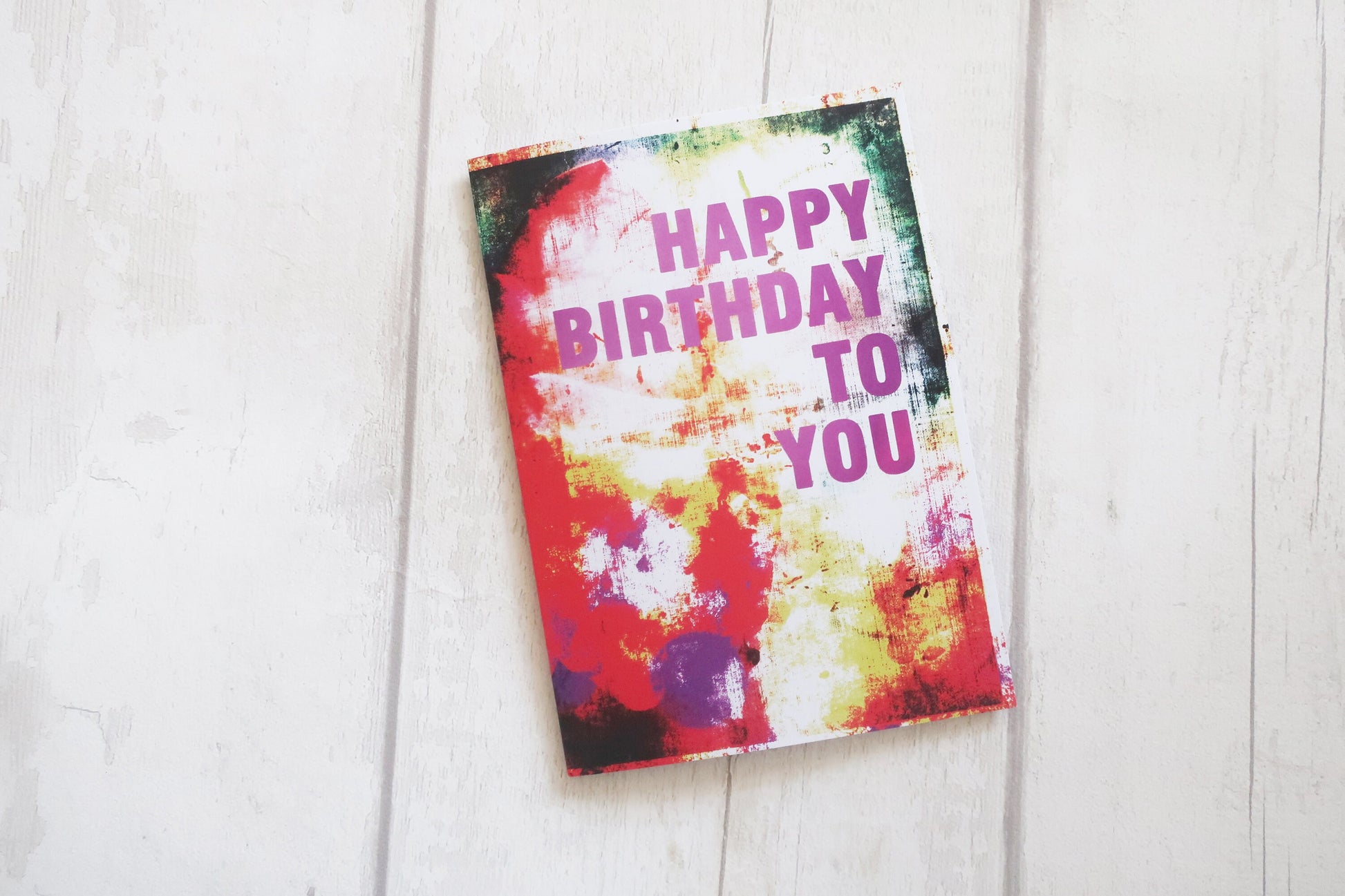 Colorful birthday card with 'Happy Birthday To You' text on a white wooden surface