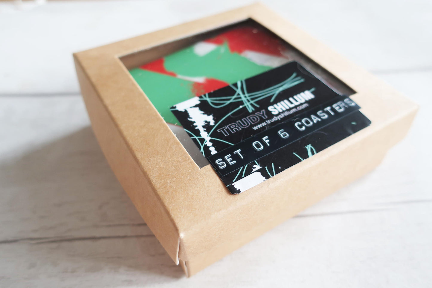 Box of Trudy Shillum coasters with a colorful design on a white surface