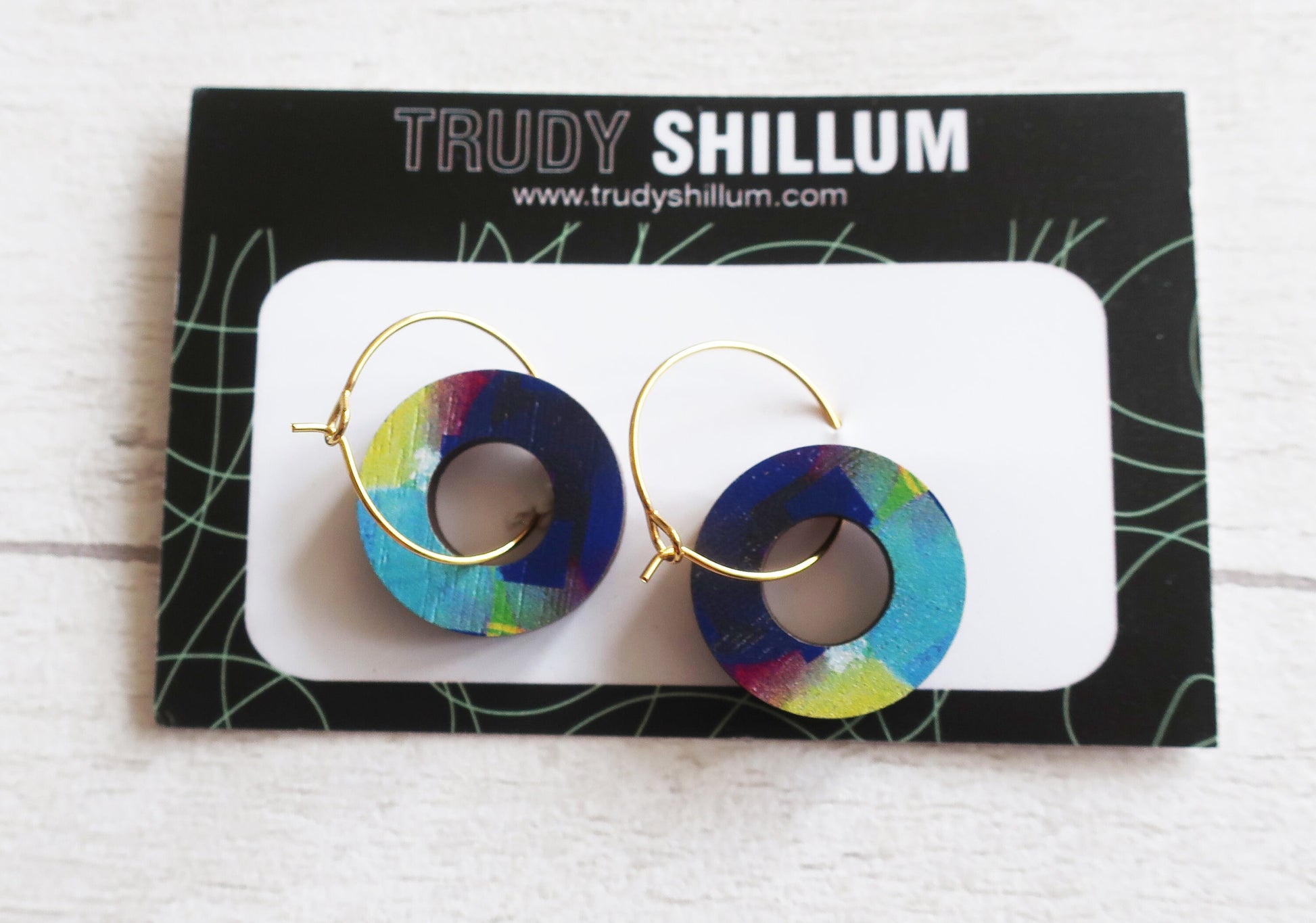 Colorful hoop earrings on a Trudy Shillum branded card.