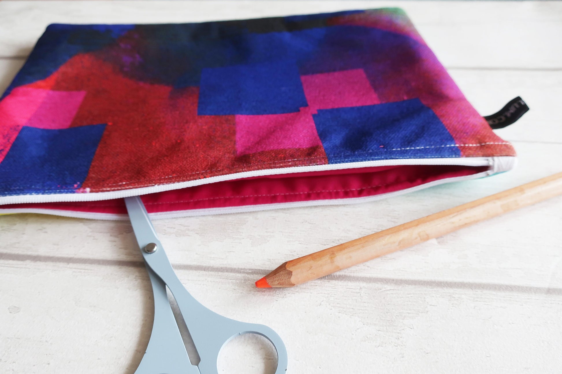 Colorful fabric pouch with a pencil and scissors on a wooden surface