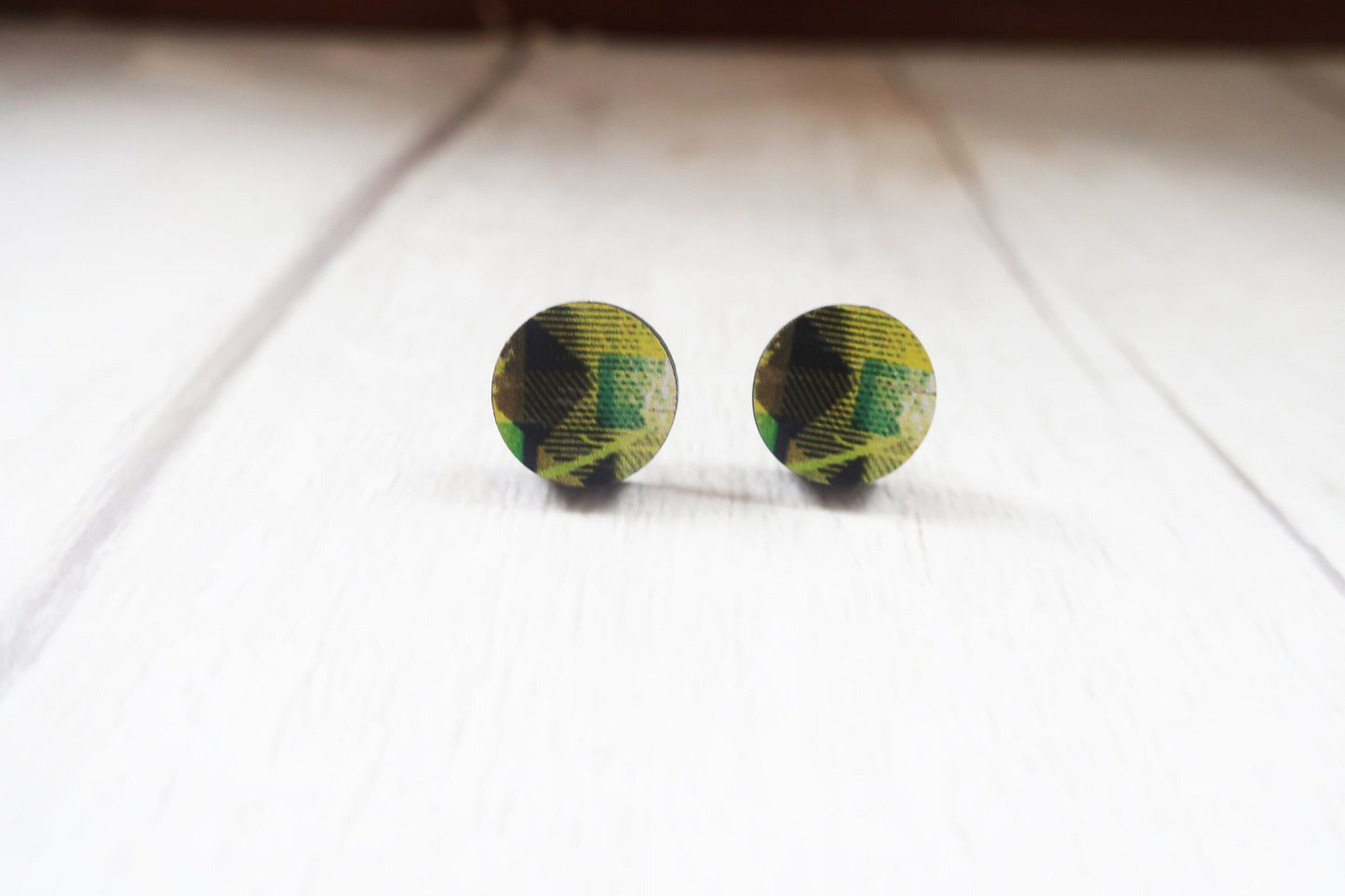 Round green and black patterned earrings on a white surface