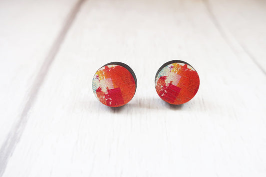 Pair of round earrings with red and white design on a white background
