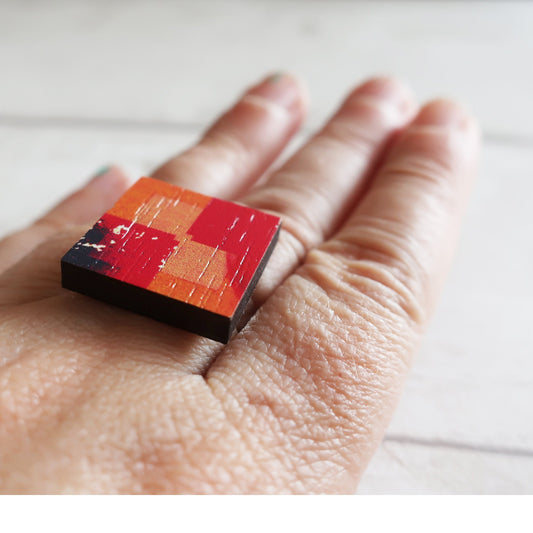 Small square wooden ring  with a checkered pattern on a person's hand