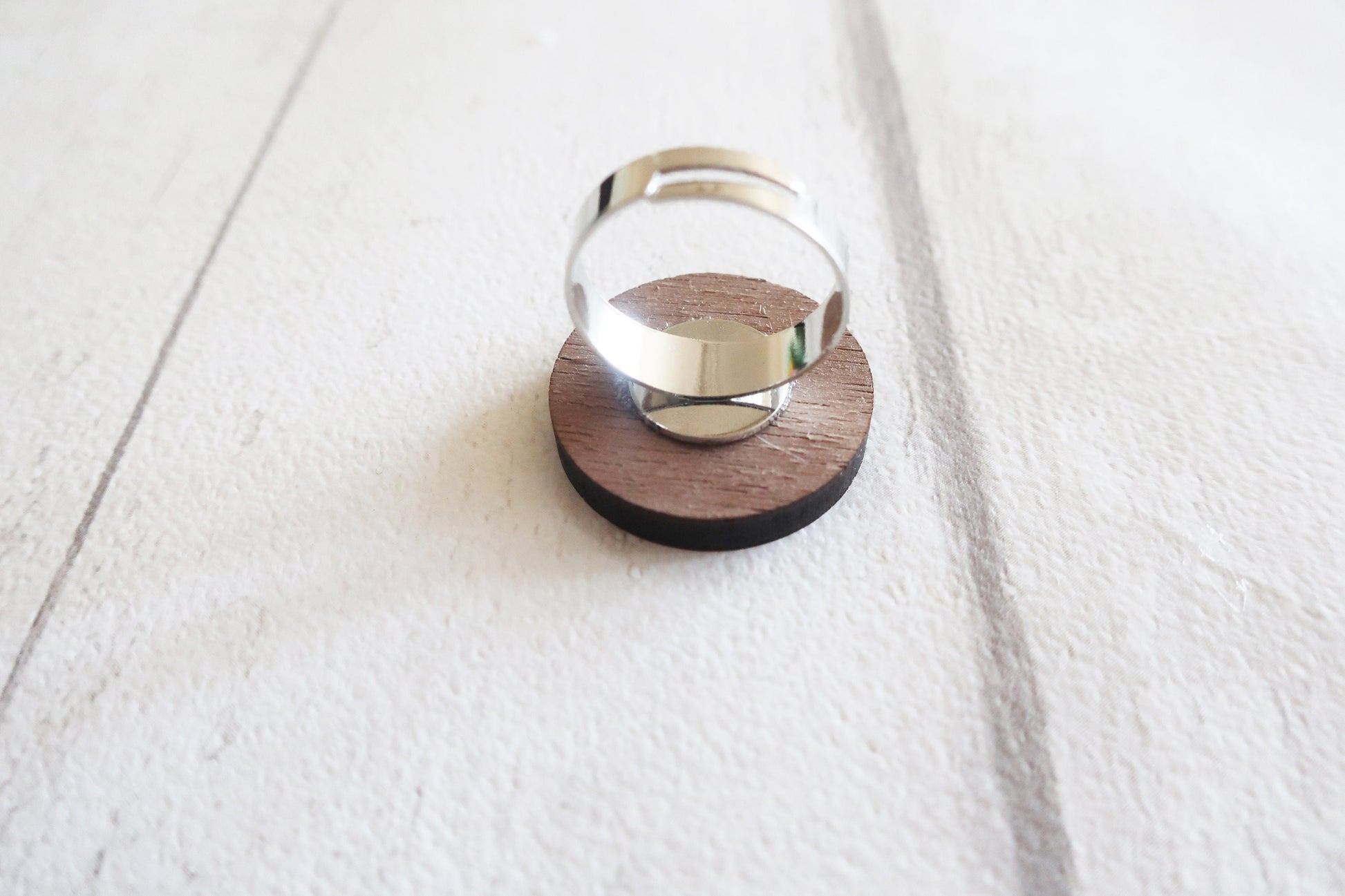 Silver ring on a wooden stand against a white background