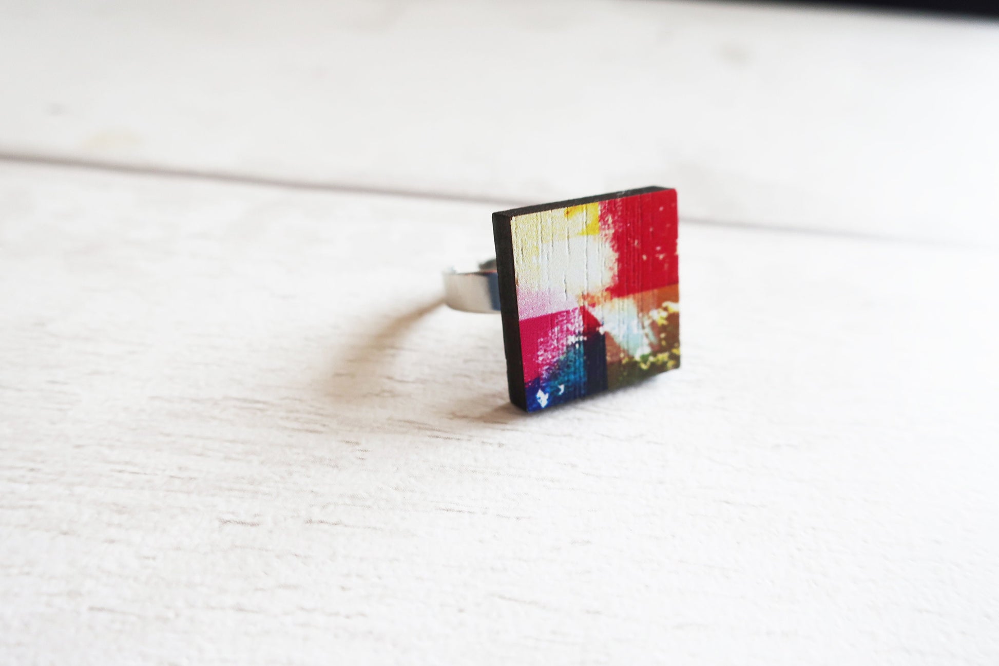 Square ring with colorful abstract design on a white surface