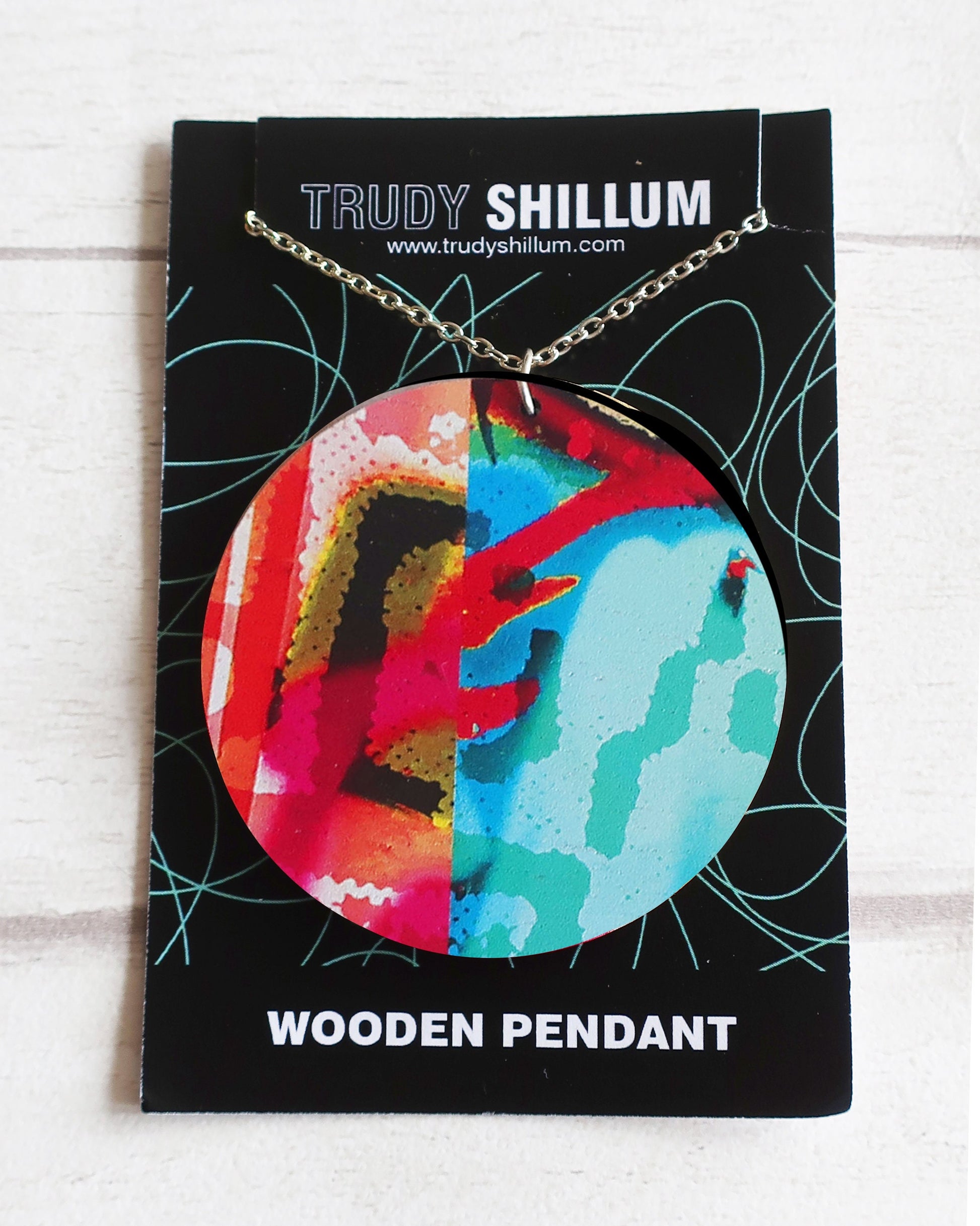 Colorful wooden pendant on a Trudy Shillum branded card with a white background