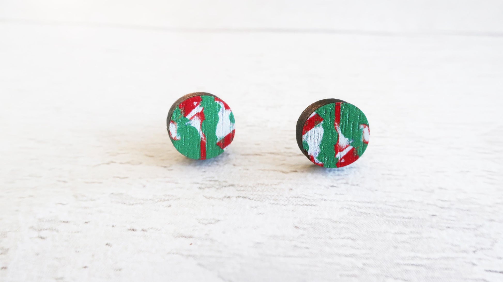 Pair of round earrings with green and red pattern on a white background