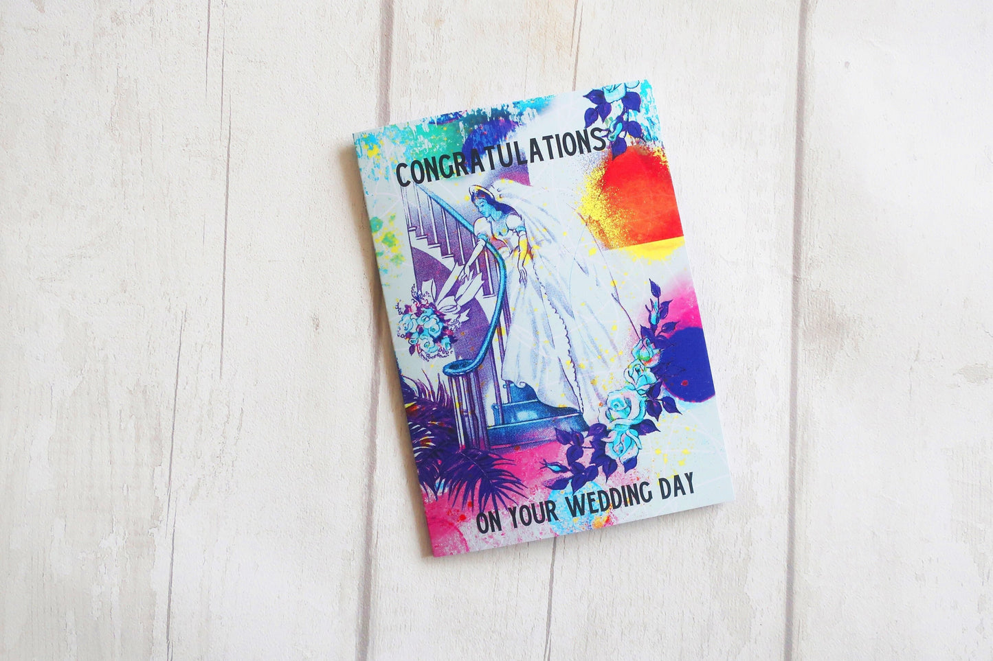 Colorful wedding card with 'Congratulations on your wedding day' text on a light wooden surface.