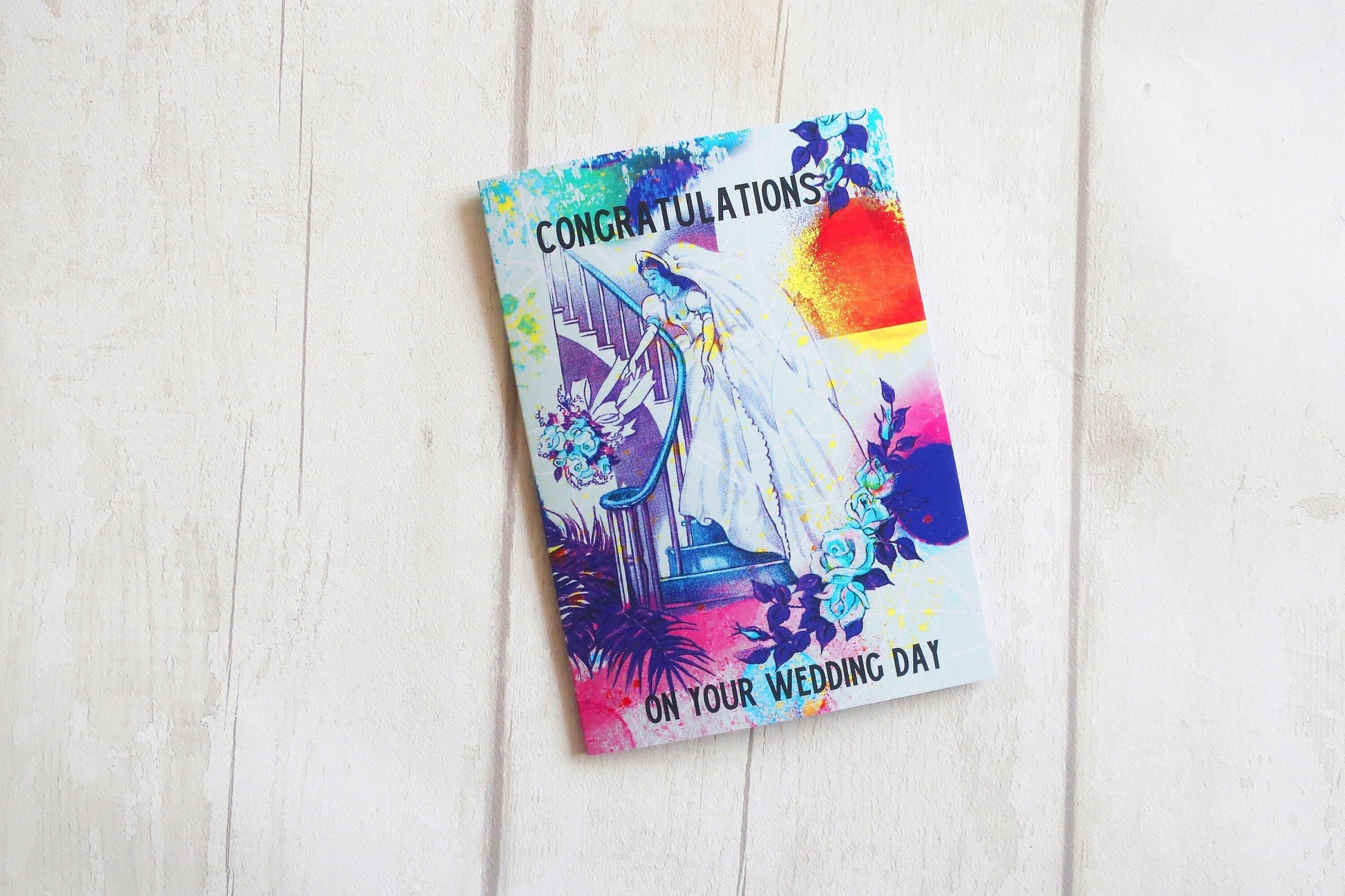 Colorful wedding card with 'Congratulations on your wedding day' text on a light wooden surface.