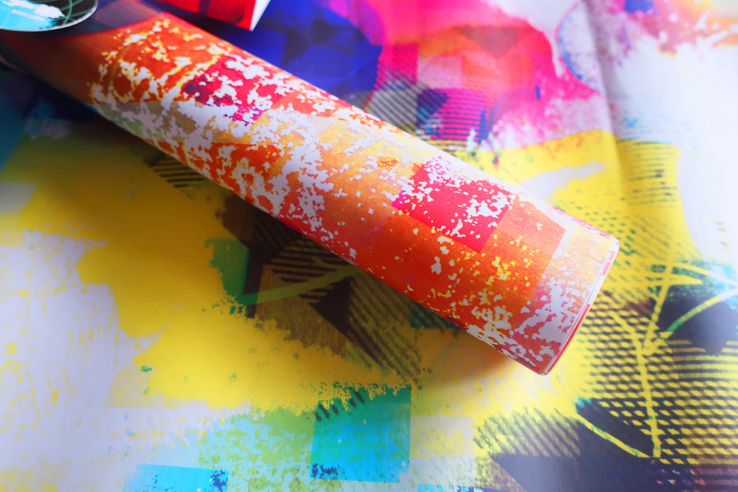 Colorful cylindrical wrapping paper with white speckles on a multicolored background