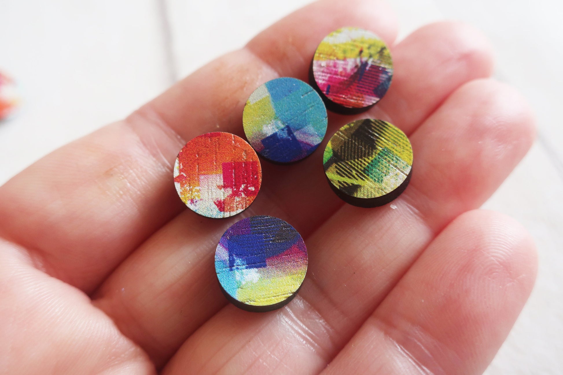 Colorful earrings held in a hand with a blurred background