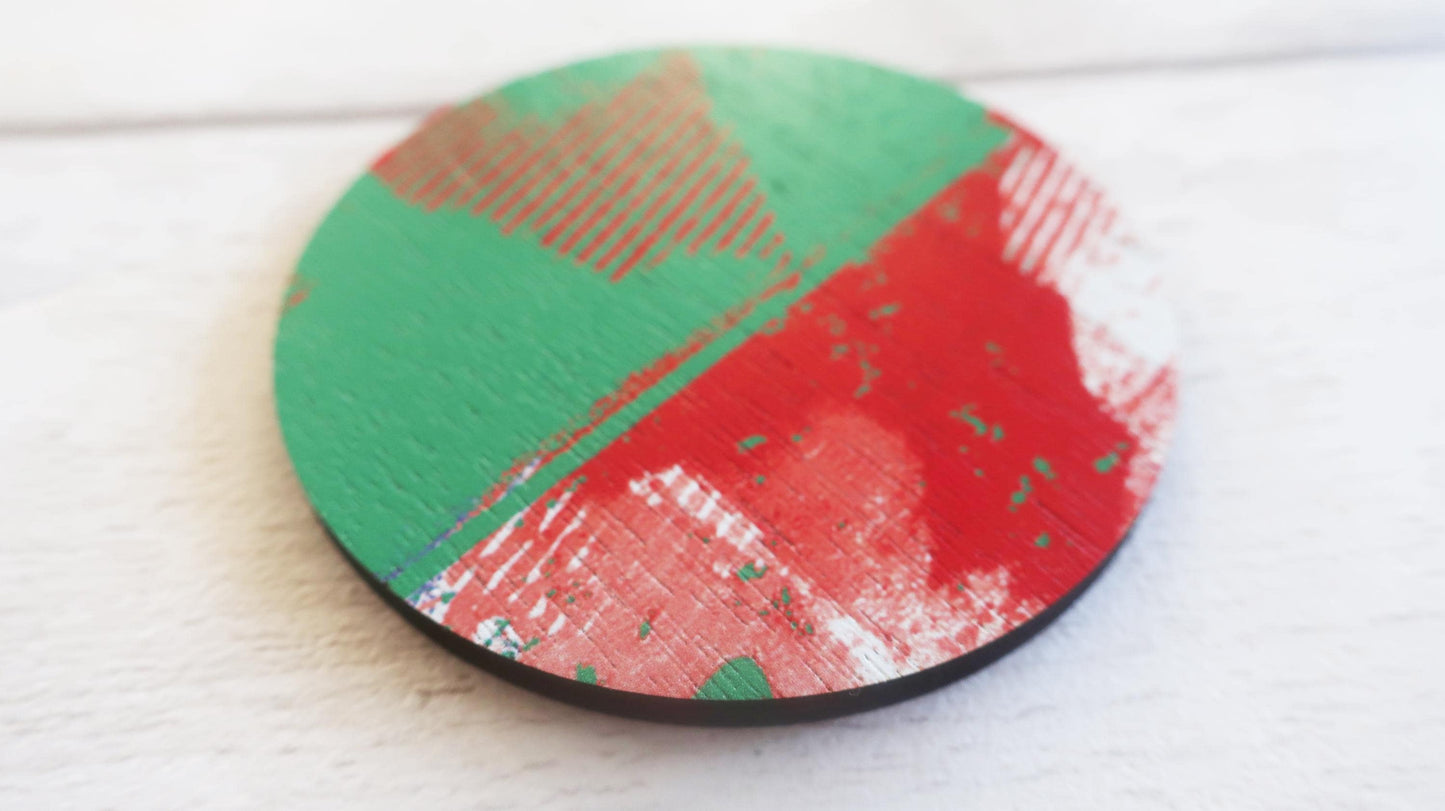 Round brooch with green and red design on a white surface