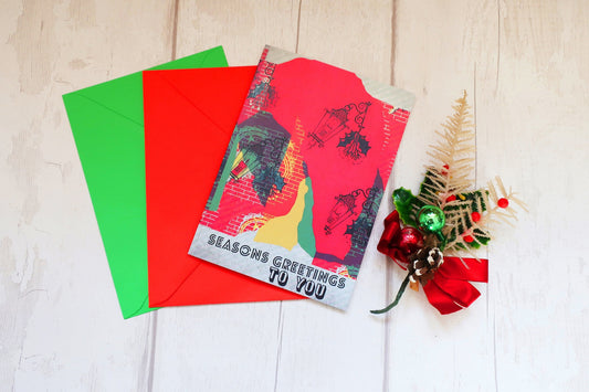 Christmas card with colorful design and envelopes on a wooden surface.