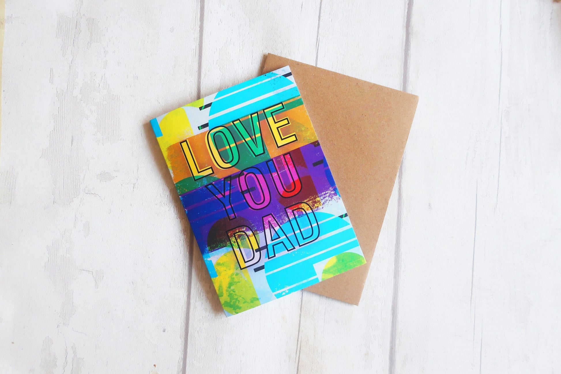Colorful card with 'Love You Dad' text on a wooden surface