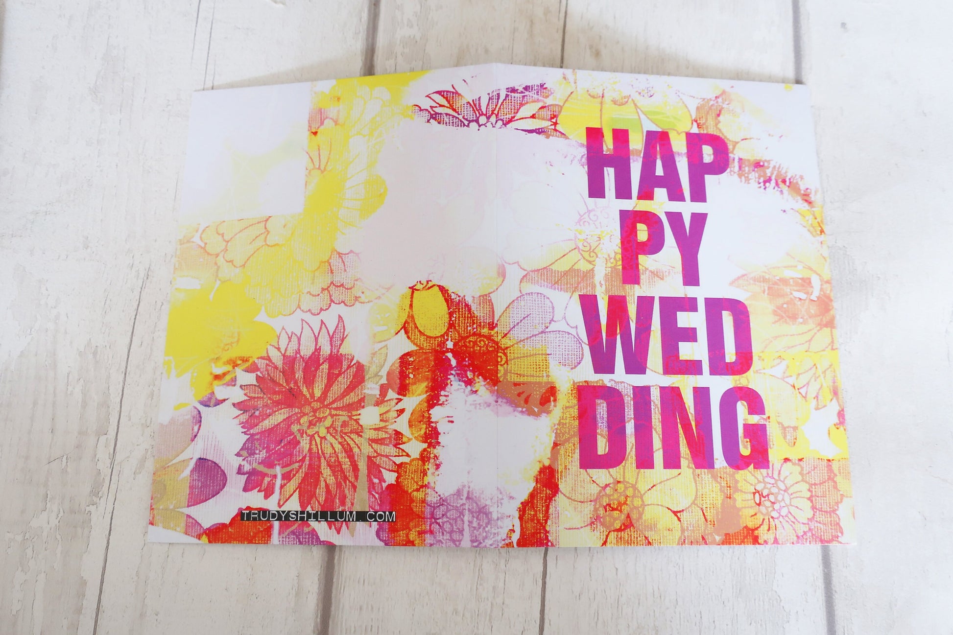 Colorful card with 'Happy Wedding' text on a wooden surface