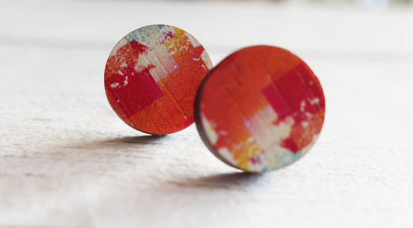 Colorful round earrings on a light wooden surface