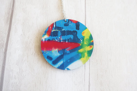 Colorful abstract design on a round pendant against a white background