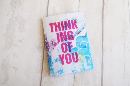 Greeting card with 'Thinking of You' text on a light wooden surface