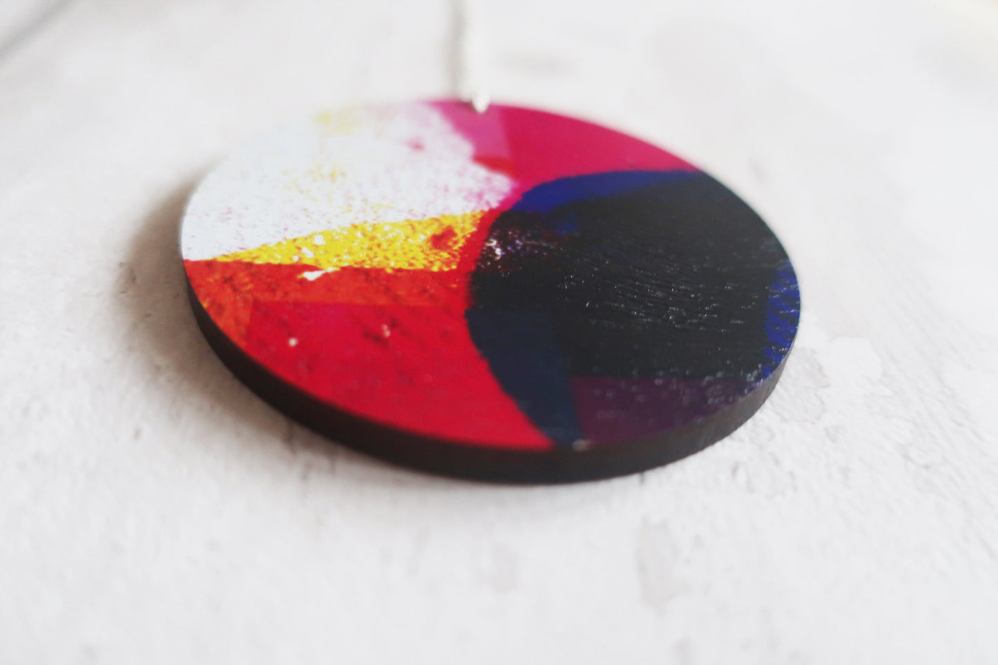 Round colorful necklace with a gradient of red, yellow, and black on a white background