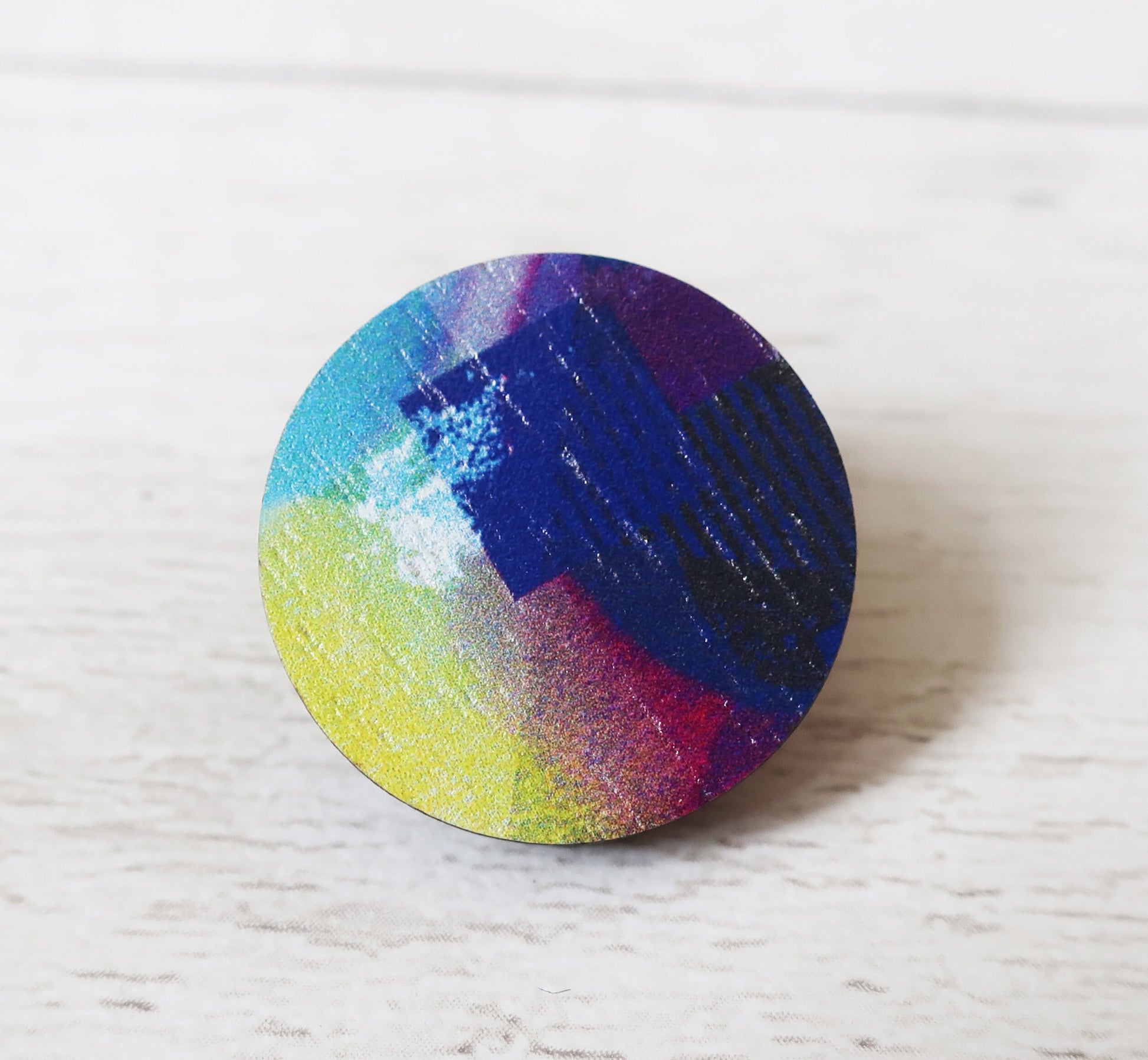 Round colorful pin badge on a white textured surface
