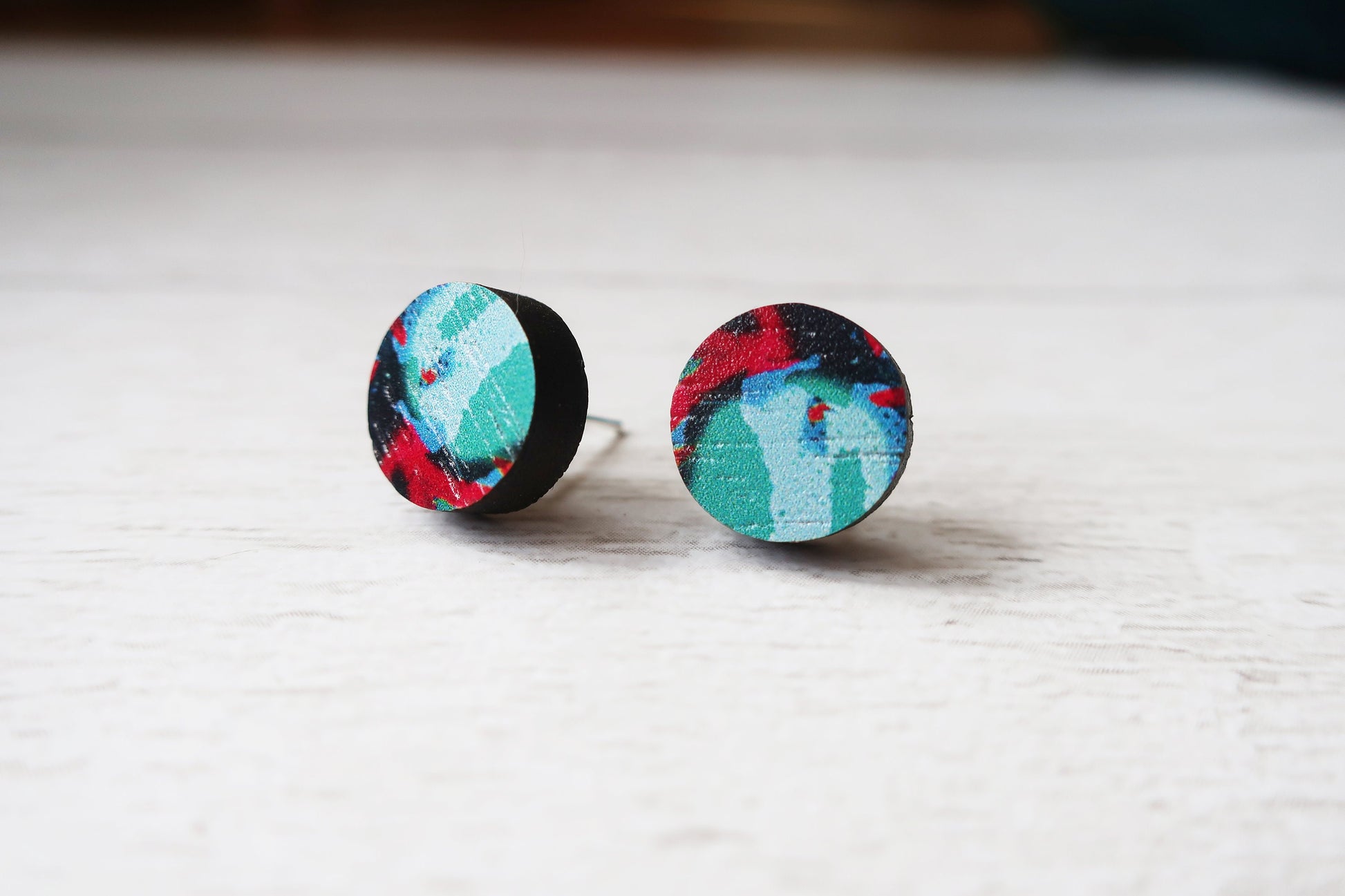 Colorful round earrings on a light wooden surface