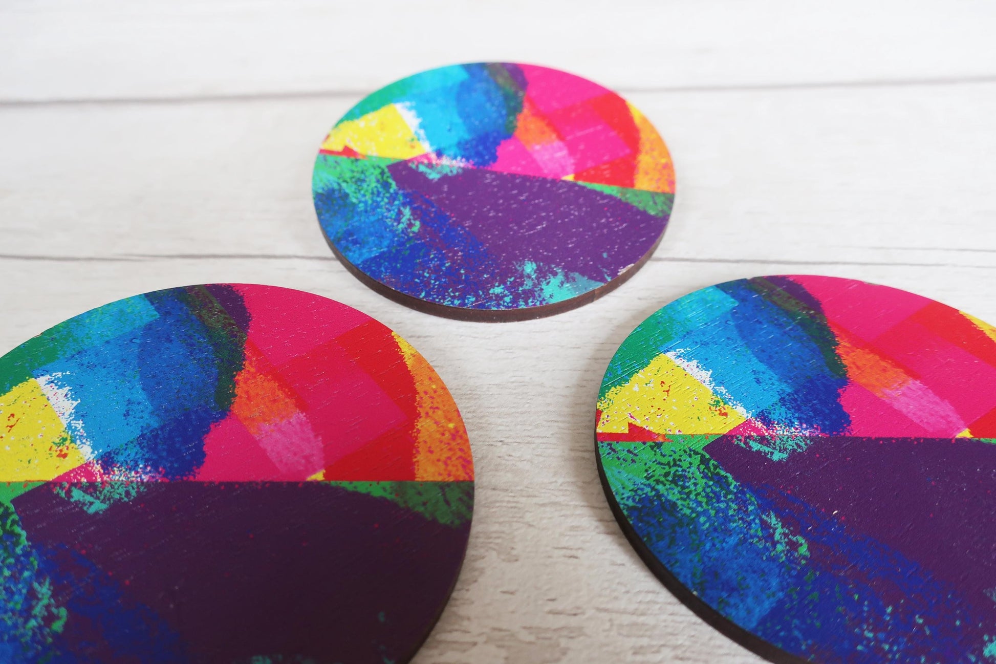 Three colorful circular brooches on a white surface