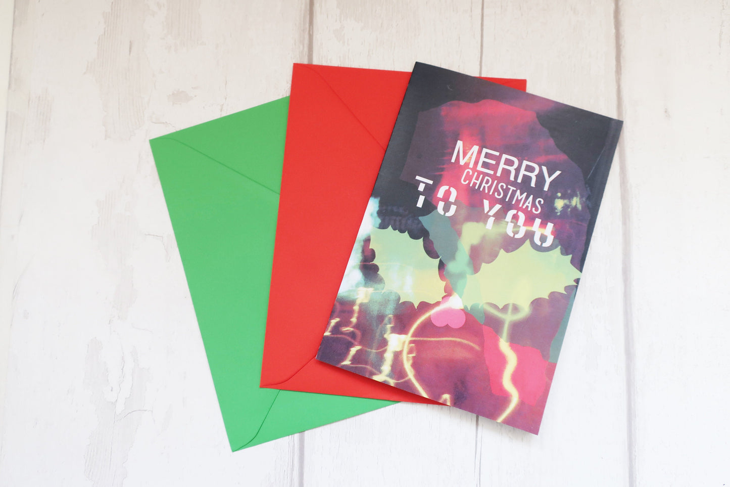 Colorful Christmas card with 'Merry Christmas to you' text on a white wooden surface.