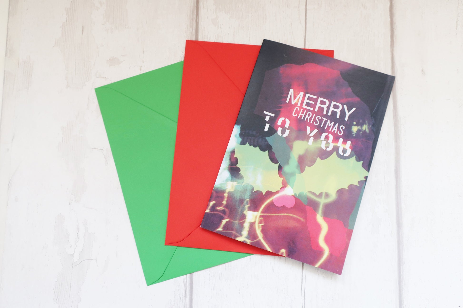 Colorful Christmas card with 'Merry Christmas to you' text on a white wooden surface.