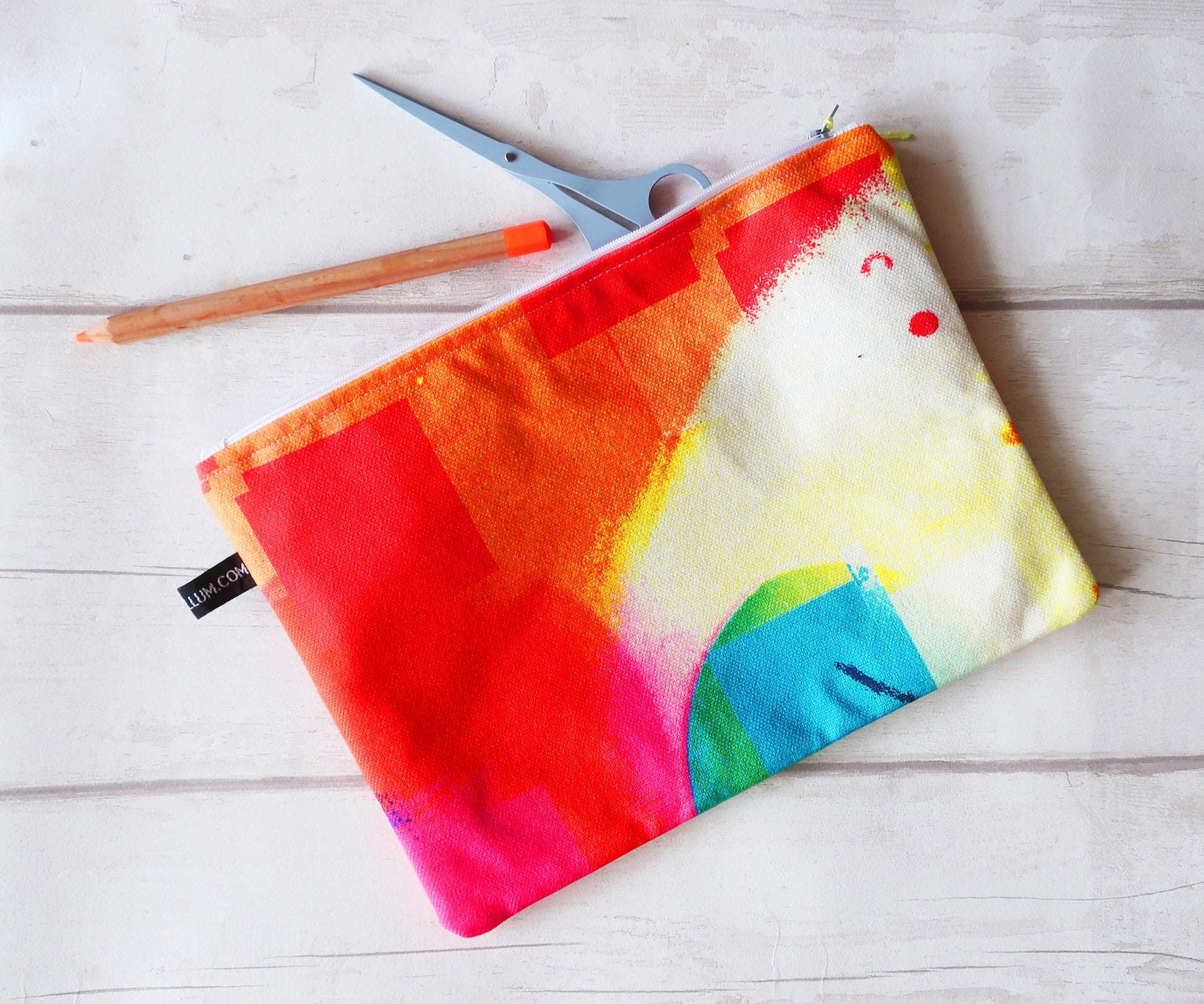 Colorful tie-dye pouch with scissors on a light wooden surface