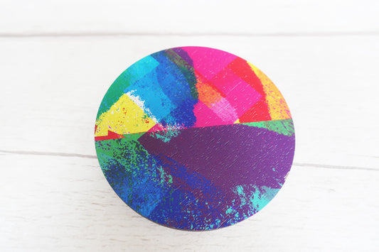 Colorful circular brooch with abstract design on a white background