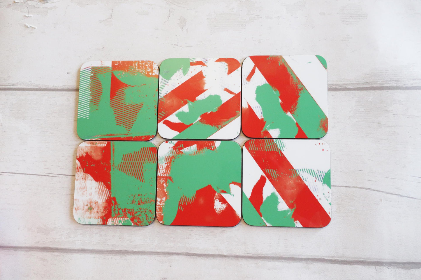Set of six red and green patterned coasters on a light wooden surface