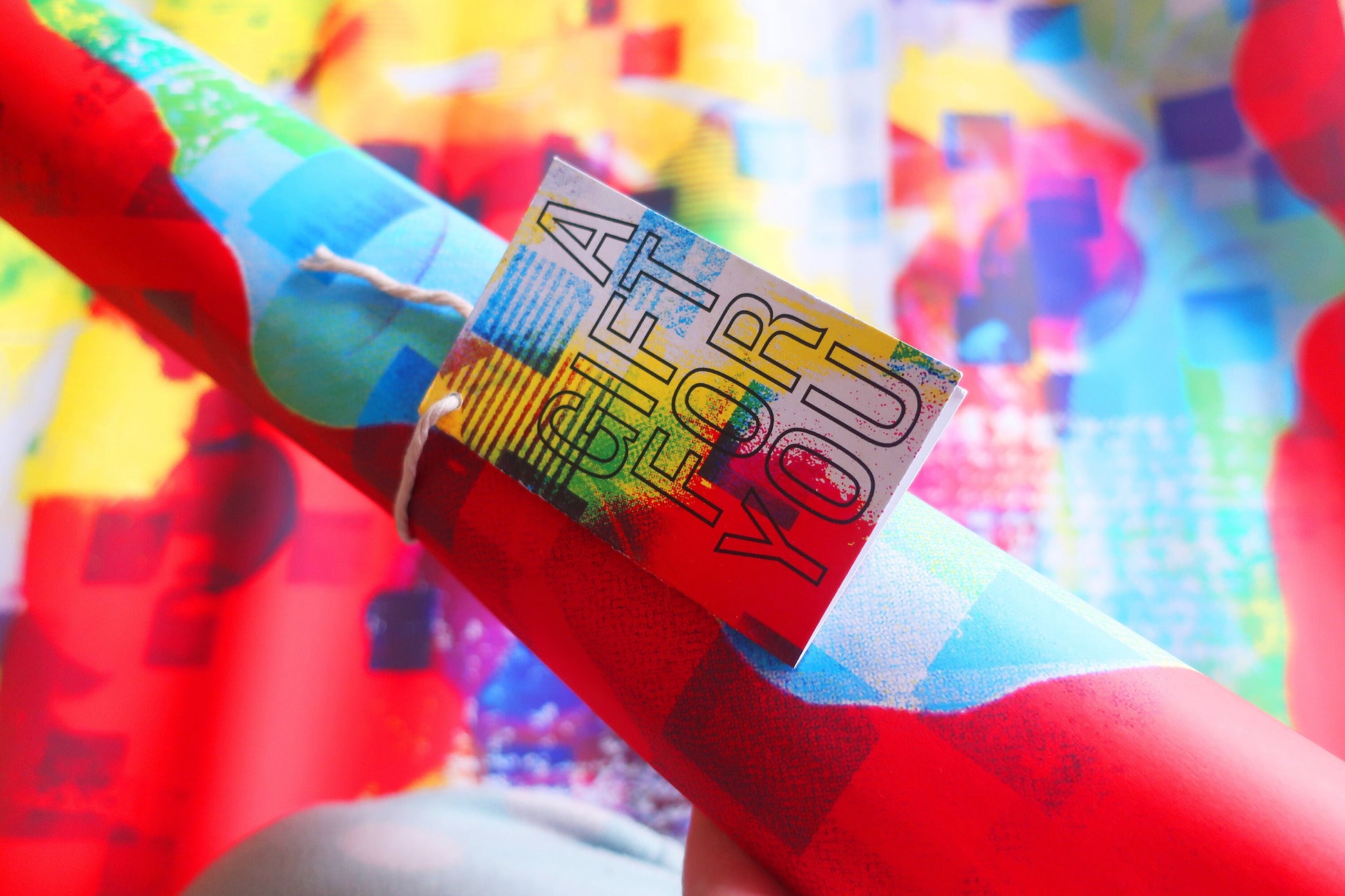 Colorful gift tag on a red and green gift wrap with a blurred colorful background