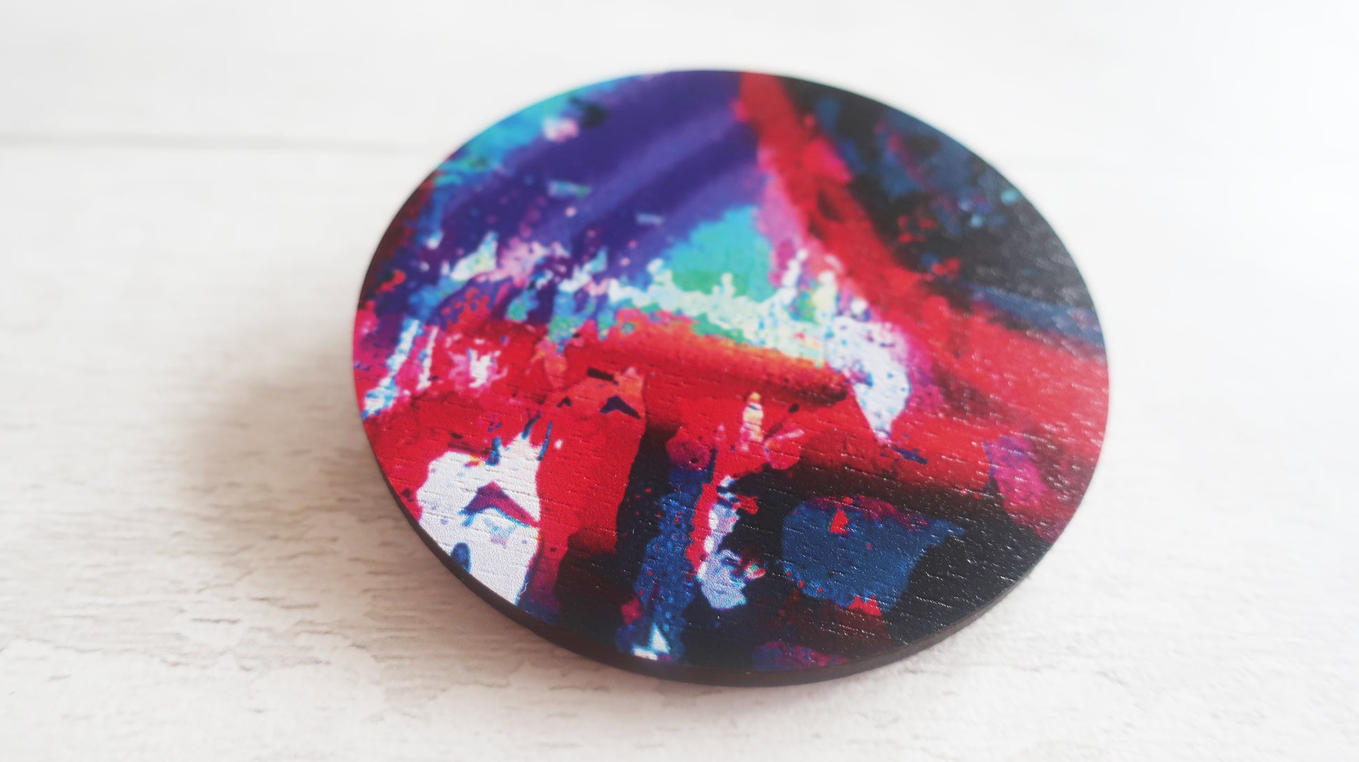 Colorful abstract design on a round brooch against a white background