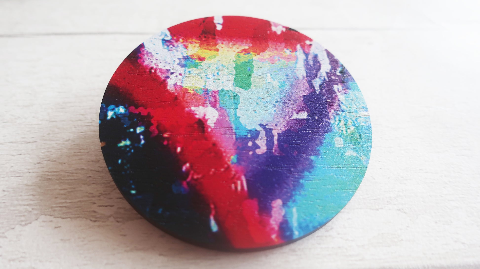 Colorful round brooch  with a tie-dye pattern on a white surface
