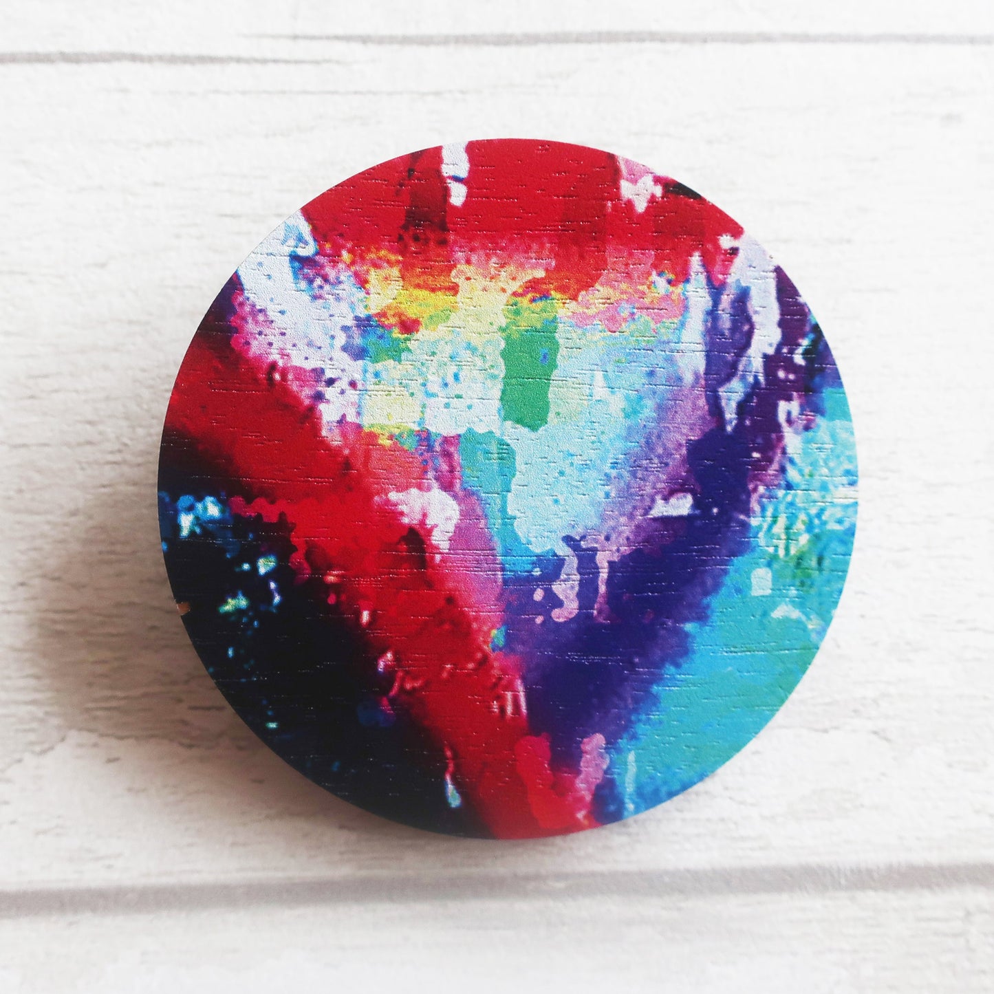 Colorful tie-dye brooch on a white wooden surface