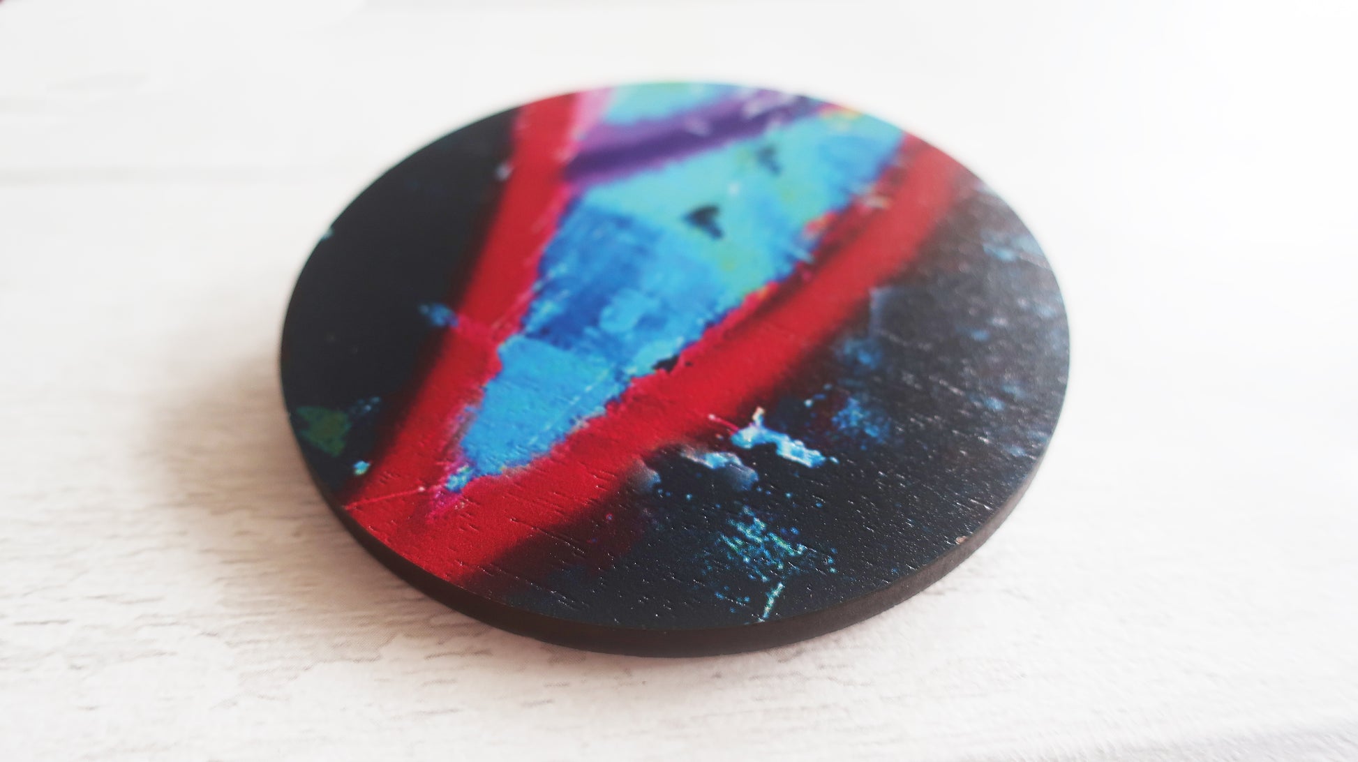 Colorful circular brooch with a black background on a white surface