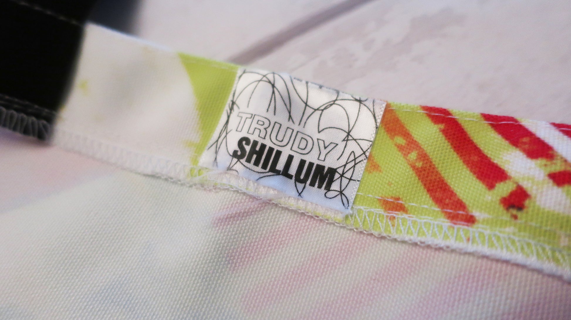 Close-up of a label with 'Trudy Shillum' on a tote bag with colorful pattern