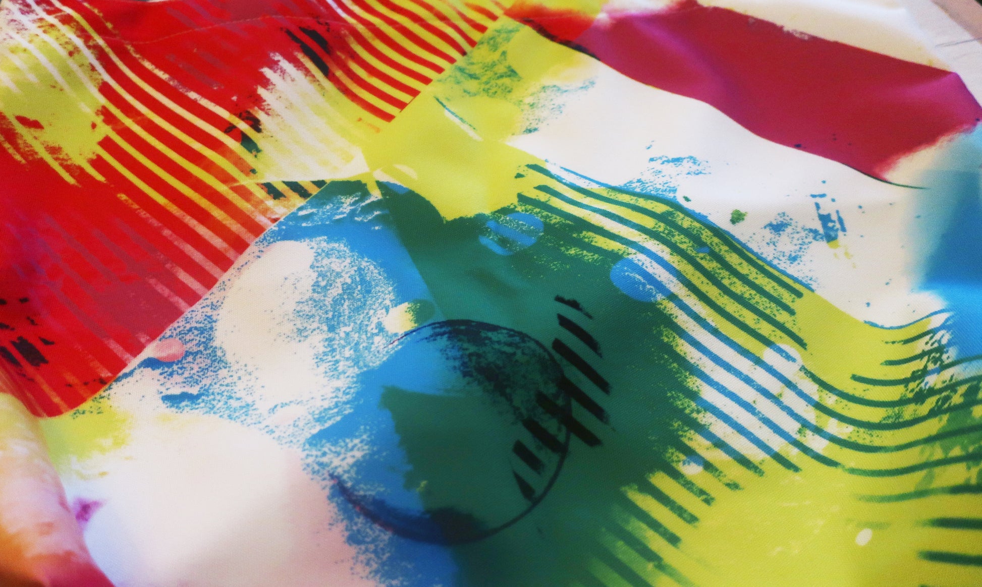 Colorful abstract fabric with vibrant red, yellow, blue, and green strokes.