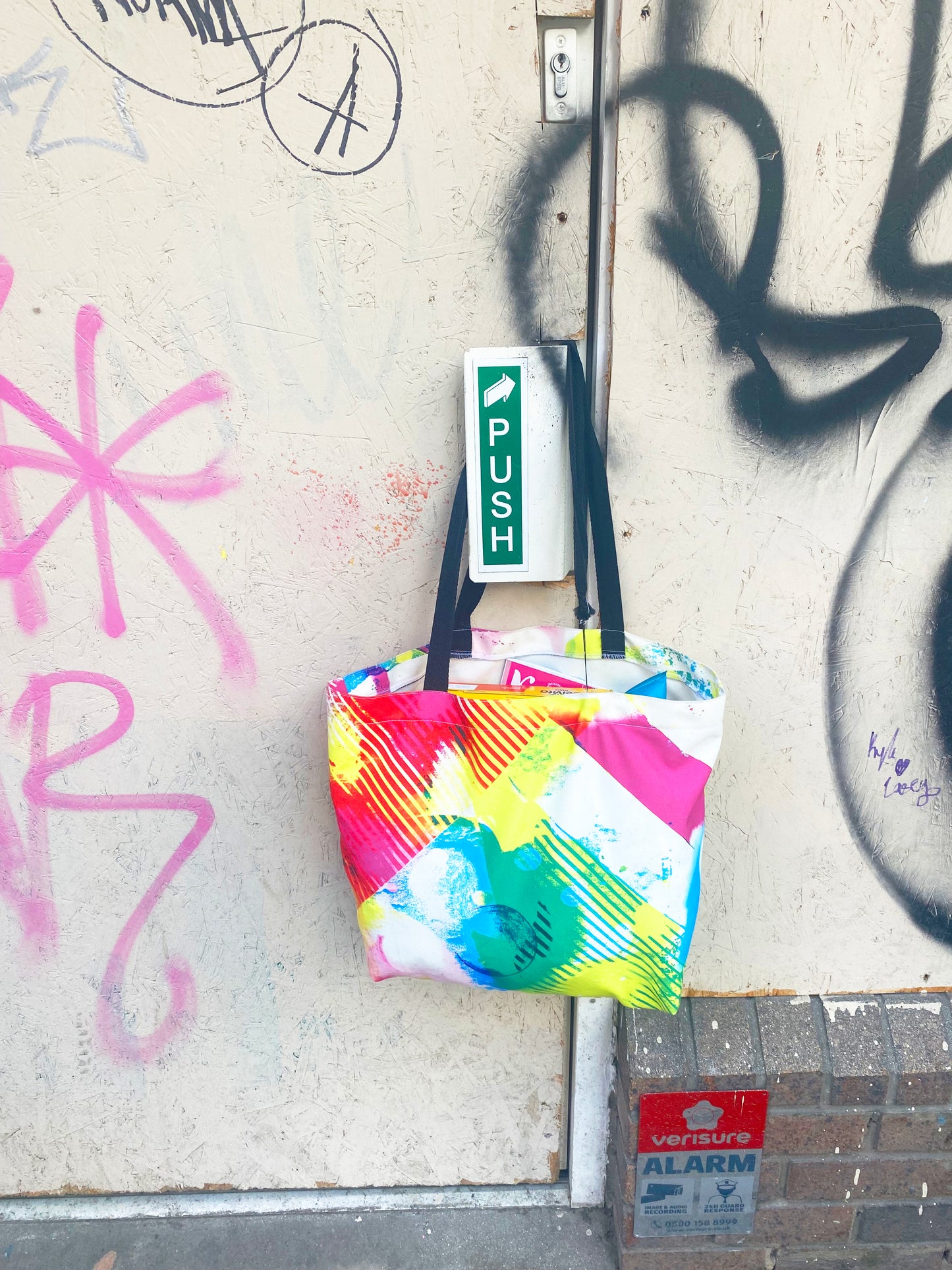 Colorful tote bag hanging on a wall with graffiti