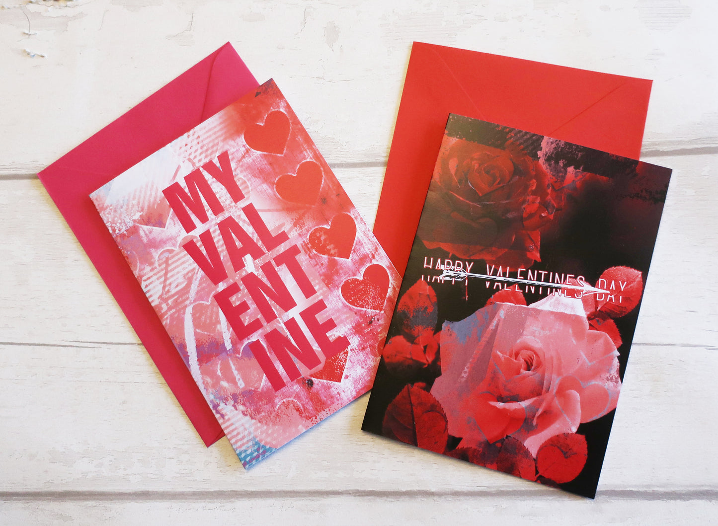 Two Valentine's Day cards with red envelopes on a white wooden surface