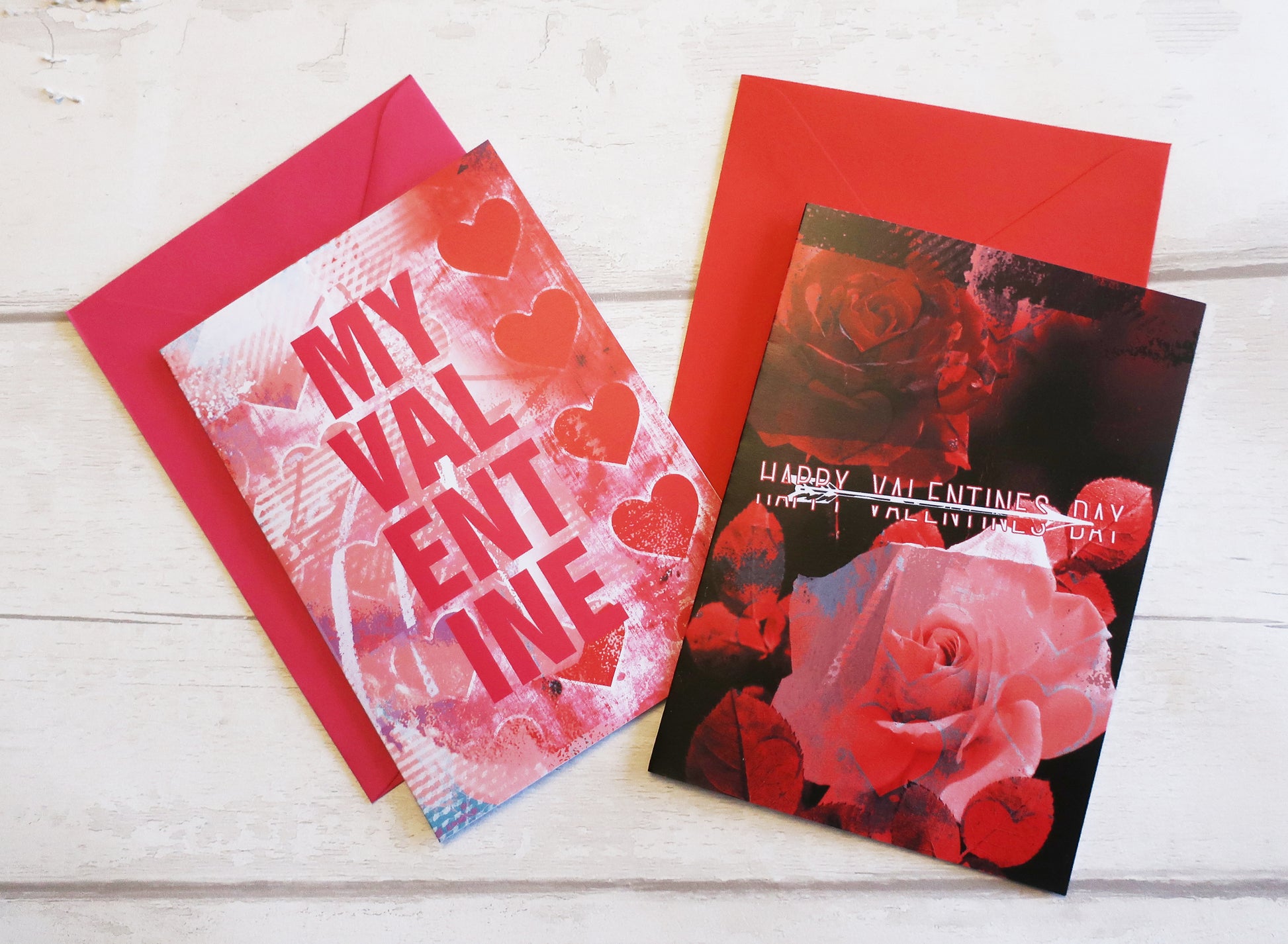 Two Valentine's Day cards with red envelopes on a white wooden surface