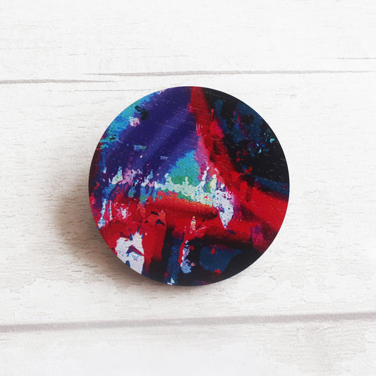 Round colorful brooch on a white wooden surface