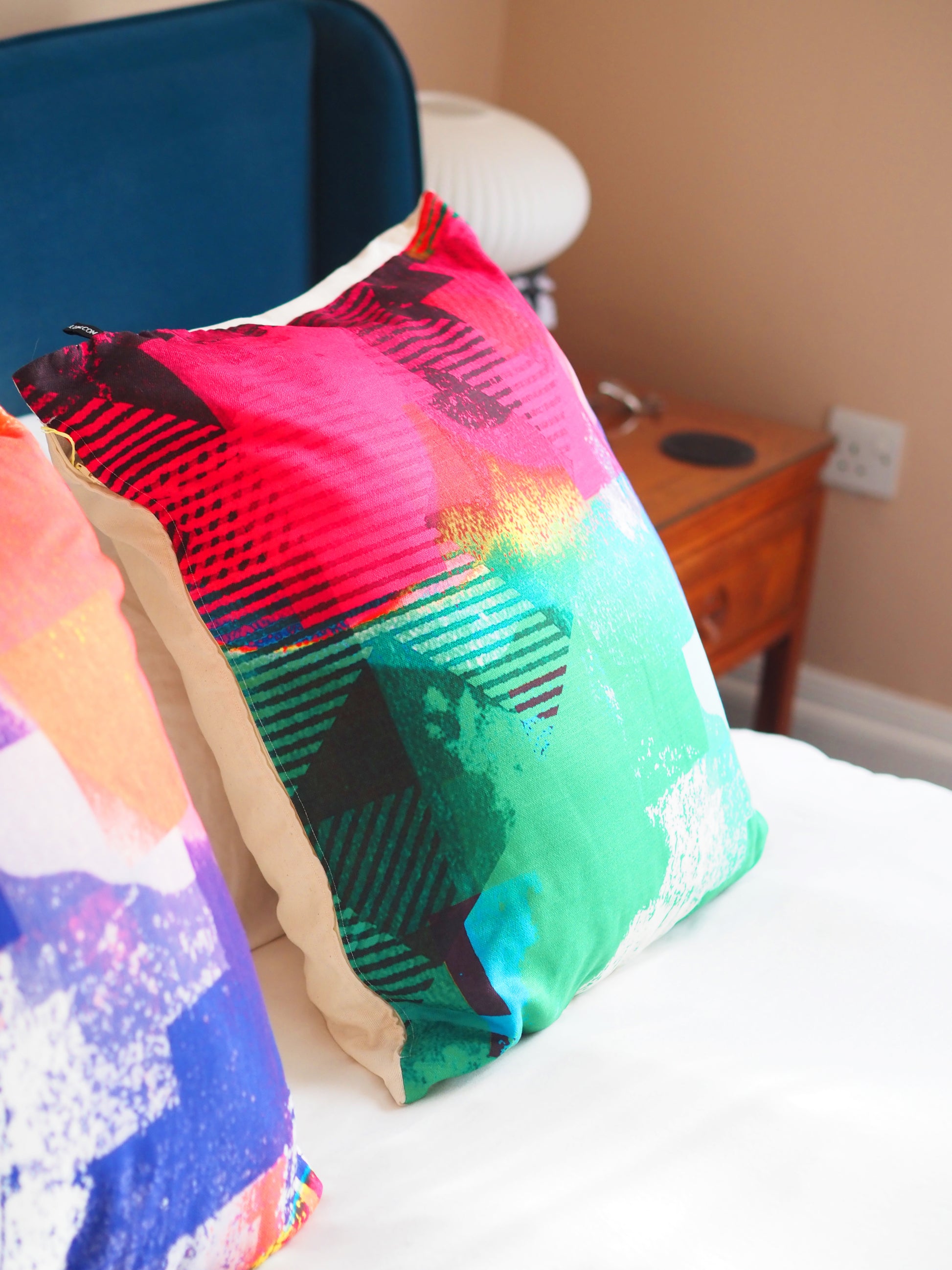 Colorful patterned pillow on a bed with a blurred background